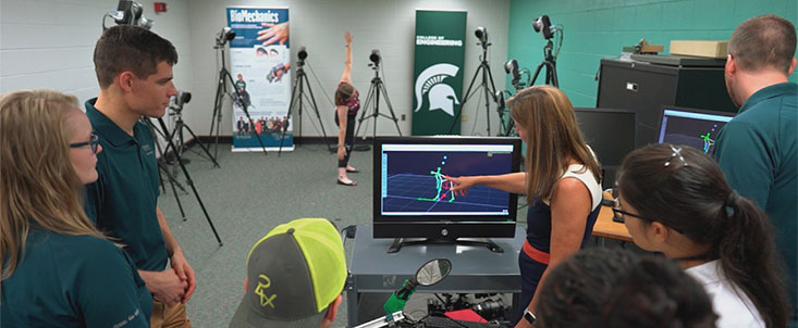 Doctor Tammy Reid Bush with her students look at a computer. 