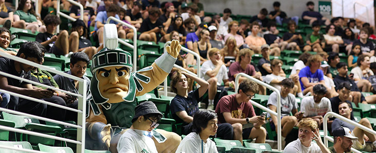 Sparty sitting with a crowd of students